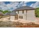 View of home's brick exterior with dark roof and covered patio, surrounded by undeveloped landscape at 4222 Matisse Ln, Fairburn, GA 30213