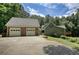 Home exterior featuring a large driveway and two-car garage with stone accents, set amidst a green landscape at 116 Woolsey Creek Trl, Fayetteville, GA 30215