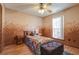 Stylish bedroom features a unique painted wall, a ceiling fan, and a comfortable bed and ottoman at 121 St Albans Way, Peachtree City, GA 30269