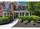 Close-up of brick home's entrance featuring a covered porch with white columns and manicured landscaping at 7014 E Hills Way, Woodstock, GA 30189