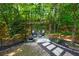 Secluded outdoor retreat featuring a pergola, stone path, and seating area surrounded by lush landscaping at 7014 E Hills Way, Woodstock, GA 30189