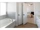 Bright bathroom with a soaking tub and open doorway to the bedroom with ceiling fan at 20 Geranium Ln, Covington, GA 30016