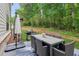 Outdoor patio with dining set, umbrella, grill, and view of the wooded backyard at 172 Aspen Hall Dr, Canton, GA 30115