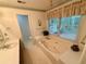 A bright bathroom featuring a large soaking tub, a window for natural light, and a vanity at 235 Creekside Way, Mcdonough, GA 30252