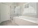 This bathroom features a glass enclosed shower and tub with tile surround and blinds at 4170 Haynes Mill Nw Ct, Kennesaw, GA 30144