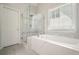 This bathroom features a glass enclosed shower and tub with tile surround and blinds at 4170 Haynes Mill Nw Ct, Kennesaw, GA 30144