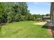 Spacious backyard with lush green grass, mature trees, black iron fence, and a concrete patio at 6995 Tybridge St, Cumming, GA 30040