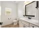 Well-lit bathroom featuring a vanity with a framed mirror, toilet, and a window letting in natural light at 6995 Tybridge St, Cumming, GA 30040