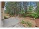 View of wooded backyard with mature trees and a small patio area at 2760 Lions Gate Dr, Cumming, GA 30041