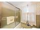 Vintage bathroom featuring textured glass shower door, neutral tile, and a window with floral curtains at 3497 Highway 5, Douglasville, GA 30135