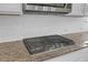 Close up shot of cooktop on granite countertop with white tile backsplash and stainless steel microwave above at 2520 Wood Fern Ln, Cumming, GA 30041
