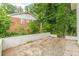 Backyard area featuring a low brick retaining wall, mature trees, and a view of a neighboring brick home at 3275 Clifton Church Se Rd, Atlanta, GA 30316
