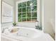 Bright bathroom featuring a luxurious soaking tub with jets and a large window overlooking the backyard at 3874 Lost Oak Dr, Buford, GA 30519