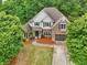 Charming two-story home with brick and shingle accents, surrounded by mature trees and lush landscaping at 3874 Lost Oak Dr, Buford, GA 30519