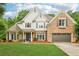 Charming two-story home with a brick facade, lush landscaping, and a welcoming entrance perfect for Gathering living at 3874 Lost Oak Dr, Buford, GA 30519