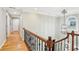Hallway featuring beautiful hardwood floors, elegant lighting fixtures, and a staircase with rod iron spindles at 3874 Lost Oak Dr, Buford, GA 30519