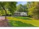 Picturesque front yard with a verdant lawn, mature trees, and a charming home with covered porch at 1150 Kennesaw Due West Nw Rd, Kennesaw, GA 30152