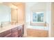 Bright bathroom featuring double sinks and a soaking tub under a window at 4448 Tacoma Trce, Suwanee, GA 30024