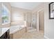 Bathroom featuring a soaking tub with tile surround and a shower with glass door at 4920 Fourth Rail Ln, Cumming, GA 30040