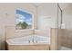 Bathroom featuring a corner soaking tub, a shower with glass door, and a large window at 4920 Fourth Rail Ln, Cumming, GA 30040