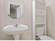 Bathroom with pedestal sink, oval mirror, toilet, and storage cabinet at 4920 Fourth Rail Ln, Cumming, GA 30040