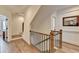 Hallway with wooden floors and stairs with dark iron railings, complemented by a framed picture and white trim at 1006 Fendley St, Woodstock, GA 30188