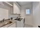 Modern laundry room features sleek sink, washer, dryer, cabinets, and tile flooring at 1006 Fendley St, Woodstock, GA 30188