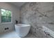 Modern bathroom featuring a freestanding tub and marble tile accent wall at 4 Bentley Trace Mnr, Atlanta, GA 30327