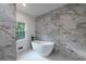 Modern bathroom with a freestanding soaking tub and marble-style tile at 4 Bentley Trace Mnr, Atlanta, GA 30327