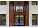 Elegant entryway features a modern steel and glass front door, and white brick with wood accents at 4 Bentley Trace Mnr, Atlanta, GA 30327