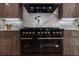 Modern kitchen features dark wood cabinetry, marble backsplash and countertops, and stainless Zline appliances at 4 Bentley Trace Mnr, Atlanta, GA 30327