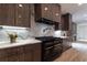 Modern kitchen features dark wood cabinetry, a marble backsplash, and a professional-grade black and gold range at 4 Bentley Trace Mnr, Atlanta, GA 30327