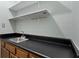 This laundry room has upper shelves, a sink, and oak cabinets with a black countertop at 4771 Pinefield Nw Dr, Acworth, GA 30102