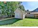 Backyard view of a small, light-yellow shed with white trim and double doors, with a background of trees at 1550 Misty Valley Dr, Lawrenceville, GA 30045