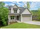 Charming two-story home surrounded by lush green trees with a covered porch and a two car garage at 216 Creek View Pl, Canton, GA 30114