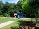 Community playground with swings and slide, set in a grassy area with mature trees, perfect for Gathering fun at 3670 Kissell Dr, Cumming, GA 30041
