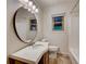 Bathroom vanity with a large round mirror, sink, window, and toilet at 3916 Green Forest Se Ln, Smyrna, GA 30082