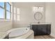 Bathroom featuring a soaking tub, vanity with a granite countertop and a round mirror at 231 Laurel Vista Dr, Canton, GA 30114