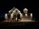 Beautiful home at night with stone and siding, landscape lighting, and a two-car garage at 231 Laurel Vista Dr, Canton, GA 30114