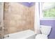 Cozy bathroom with tiled walls, tub with shower, and natural light from a window at 1206 Tred Avon Sw Way, Lilburn, GA 30047