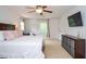 Bright bedroom with a large bed, ceiling fan, TV, ample storage, and view of a cozy blue couch at 1206 Tred Avon Sw Way, Lilburn, GA 30047