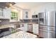 Modern kitchen design with stainless steel refrigerator, white cabinets, granite countertops, and a window view at 1216 Oleander Sw Dr, Lilburn, GA 30047