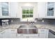 Well-lit kitchen showcases a stainless steel sink, granite countertops, white cabinets, and elegant backsplash at 1216 Oleander Sw Dr, Lilburn, GA 30047