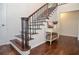 Elegant staircase features dark wood steps, iron railings and a console table with hardwood floors at 1216 Oleander Sw Dr, Lilburn, GA 30047