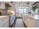 Bright kitchen features white cabinets, stainless steel appliances, and a farmhouse sink under a large window at 23 Sunset Se Rdg, Cartersville, GA 30121