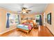 Cozy bedroom featuring hardwood floors, a ceiling fan, and windows with blue curtains at 2511 Oak Ave, Tucker, GA 30084