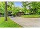 A quaint brick house surrounded by mature trees, showcasing a lush lawn and long driveway at 2511 Oak Ave, Tucker, GA 30084