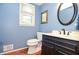Cozy powder room with a black vanity, light blue walls, and an oval mirror at 5199 Beech Forest Sw Dr, Lilburn, GA 30047