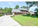 Brick home with attached garage, lush front lawn, mature trees, and long driveway at 5199 Beech Forest Sw Dr, Lilburn, GA 30047