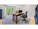 Bright home office featuring a wooden desk, ergonomic chair, decorative rug, and large window with green, leafy view at 3306 Emory Dr, Marietta, GA 30062